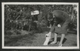Judith Hartley leaning over and petting a dog in the yard of a house