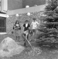 Three people watching a student shoveling dirt onto the anniversary plaque outside of Kirby Student Center