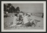 Group of three adults and a child sitting on Miami Beach