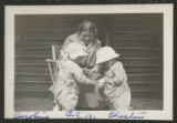 Carrie Eliza Hartley sitting in a chair with Caroline Claypool and Chester Adgate Congdon II standing beside her on the front porch of the cabin at the maple sugar camp in Trout Lake