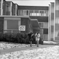 Two people walking by the "Student Health Service" sign on the front of a UMD campus building