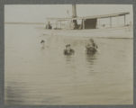 Carrie Eliza Hartley swimming with two others in Cass Lake beside a boat