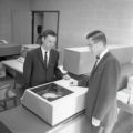 Two people standing at a machine in the Computer Center in the Computer-Laboratory Building at UMD