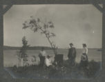 Carrie Eliza and Guilford Graham Hartley gathered with two others around a tree stump by Trout Lake