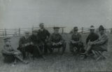 Group of suited men and soldiers sitting in a half circle.