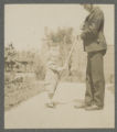 Child being pulled along a walkway on a garden spade by a young adult at the Hartley house at 1305 East Superior Street