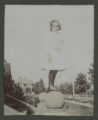 Judith Hartley standing on one of the pillars of the front steps of the Hartley house at 1305 East Superior Street