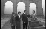 Four people standing in front of the Old Main archway