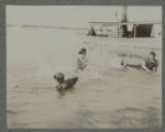 Carrie Eliza Hartley swimming with two others in Cass Lake beside a boat