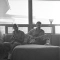 Two students sitting on couch in Kirby Student Center lounge playing guitar