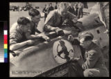 R.A.F. salvage men cutting the "little devil" design on the cowling of a Messerschmitt fighter