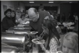 Person serving food to a child at a buffet line