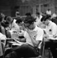 Student reading paper while sitting in desk at Freshman Orientation