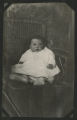 Chester Adgate Congdon II as a baby sitting in a wicker chair outside of a building