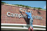 Worker cleaning the exterior sign for Solon Campus Center on the UMD campus