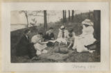 Members of the Hartley family sitting down with others for a picnic at the maple sugar camp in Trout Lake