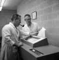 Two people sworking with a machine in the Computer Center in the Computer-Laboratory Building at UMD