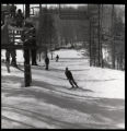 Action shot of UMD 1976 downhill skier on the slopes underneath the ski lift