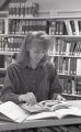 Student paging through a book in library