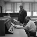 Two people working at a machine in the Computer Center in the Computer-Laboratory Building at UMD