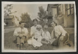 James Verner Claypool sitting with two other unidentified adults and two children sitting in the grass in front of a house