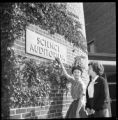 Two people standing in front of a sign on an exterior wall of the Science Building at UMD