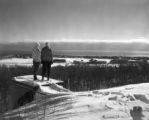 Two people standing on a cliff overlooking the UMD campus in winter