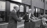 Speakers shaking hands at the dedication ceremony of the newly built Heller Hall