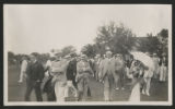 Crowd of people gathered on a golf course by a resort complex