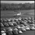 A parking lot full of cars with an airplane in the background on the UMD campus
