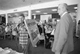 A man is holding a framed picture at the 30th anniversary celebration of Kirby Student Center