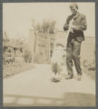 Child being pulled along a walkway on a garden spade by a young adult at the Hartley house at 1305 East Superior Street