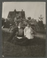 Mary Hartley and Hartley Rogers sitting by a flower bush in the yard of the Peyton House