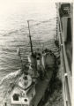 Tug boat with a life boat and a man wearing a hat on deck near a ship in harbor, probably in Bremerhaven.