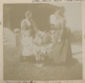 Judith Hartley standing by a flower bush with Jennie Parks and Rachel Woodward in front of the Hartley house at 1305 East Superior Street