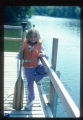 Girl at Camp Butwin with a life jacket and canoe paddle stands on a dock, Eagan, Minnesota