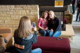 A person taking a picture of two people in front of the fireplace in Kirby Student Center