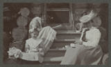 Judith and Carrie Eliza Hartley sitting with another child on the steps of a log cabin
